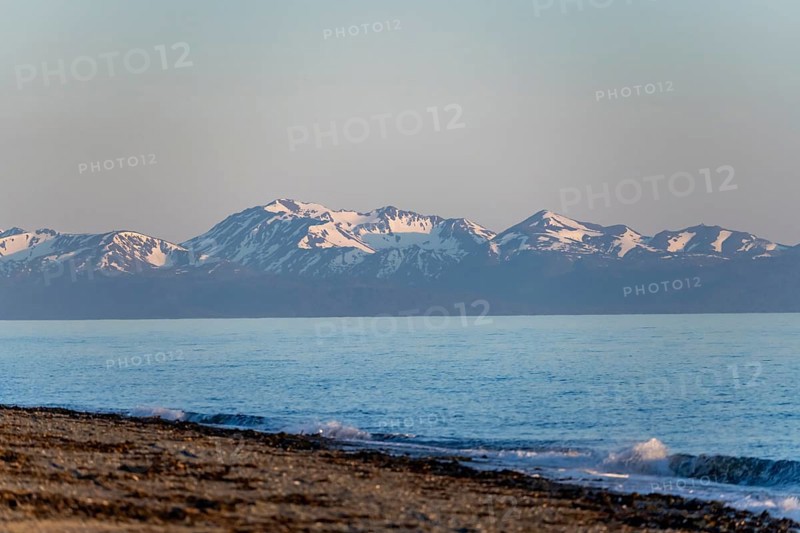 Anchor Point beach on Cook Inlet in the evening light, snowy mountain peaks of the Kenai Peninsula, Anchor River State Recreation Area, Alaska, USA