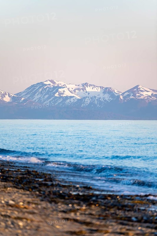 Anchor Point beach on Cook Inlet in the evening light, snowy mountain peaks of the Kenai Peninsula, Anchor River State Recreation Area, Alaska, USA