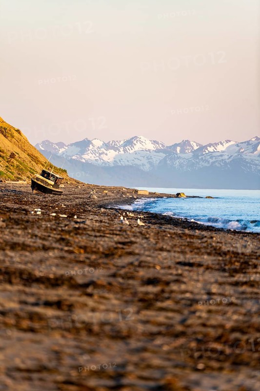 Boat on Anchor Point beach on Cook Inlet in the evening light, snowy mountain peaks, Anchor River State Recreation Area, Alaska, USA