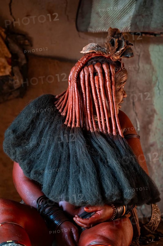 Elderly Himba woman showing her hair and jewelry, in a hut, traditional Himba village, Kaokoveld, Kunene, Namibia