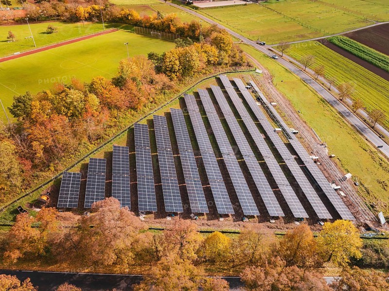 Solar systems next to a sports field, surrounded by autumn-colored trees, Bau PV Freifaechenanlage, Weil der Stadt, Germany