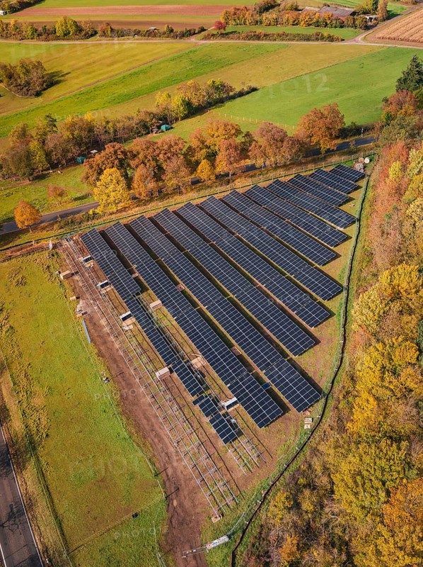 Panoramic aerial view of a solar plant surrounded by green fields and autumn trees, PV open-air plant construction, Weil der Stadt, Germany