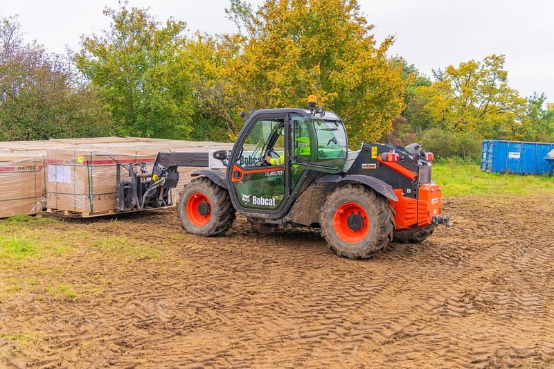 A forklift truck transports boxes across muddy soil in an autumn environment, Bau PV Freifaechenanlage, Weil der Stadt, Germany