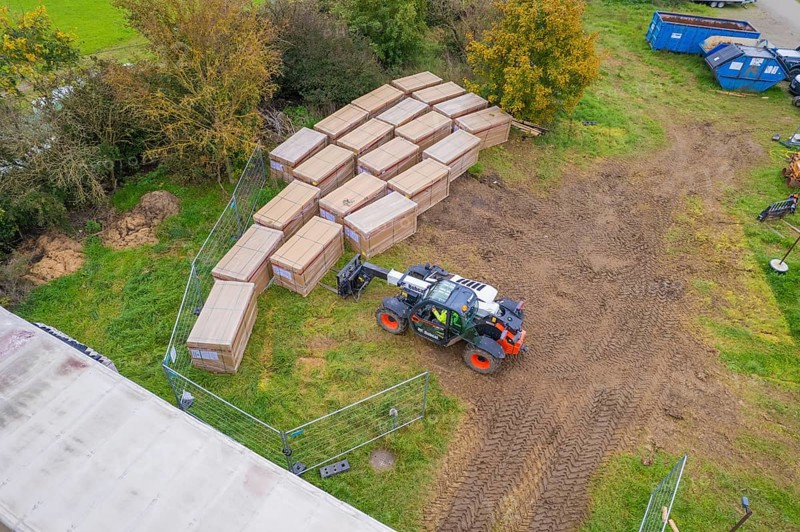 Aerial view of boxes and a forklift truck on a fenced grassy area with containers, PV Freifaechenanlage construction, Weil der Stadt, Germany