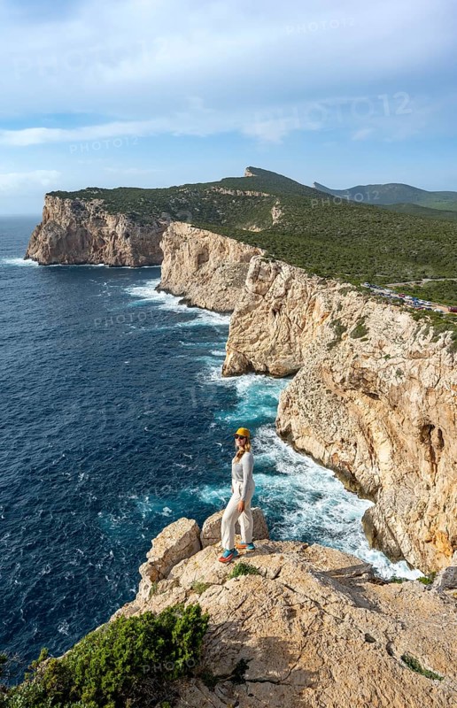 Tourist enjoying the view of steep cliffs by the sea, coastal landscape, cliffs on the Capo Caccia headland, Alghero, Sardinia, Italy