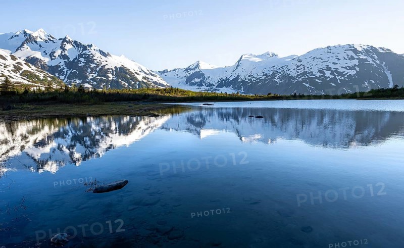 Mountain peaks with Portage Glacier glacier and snow reflected in Divide Lake mountain lake in evening light, Portage Pass Trail, Whittier, Alaska, USA