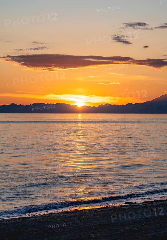 View of Cook Inlet at sunset, picturesque golden light of the midnight sun, mountains of the Aleutian Range, Anchor Point, Anchor River State Recreation Area, Alaska, USA