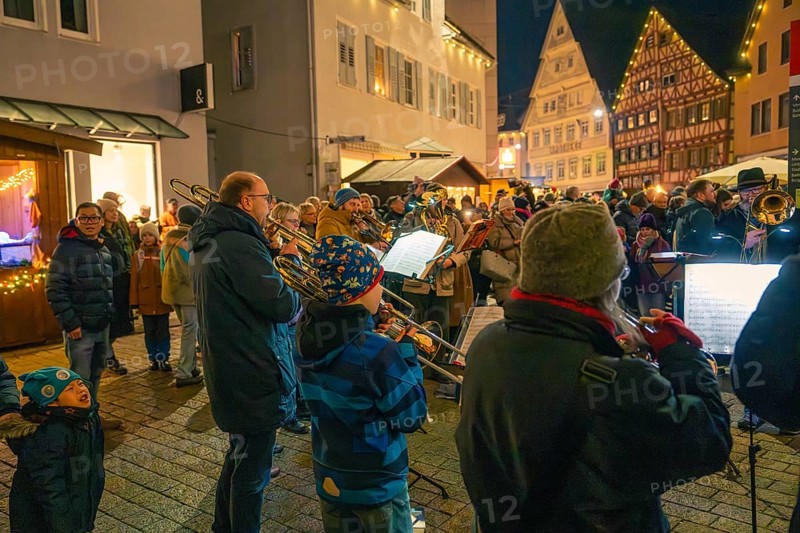 A brass band plays on a busy street surrounded by bright decorations, Christmas market 2025, Nagold, Black Forest, Calw district, Germany
