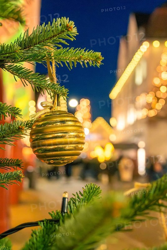 Golden Christmas ball on a pine branch surrounded by blurred lights, Christmas market 2025, Nagold, Black Forest, Calw district, Germany