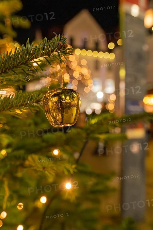 Close-up of a golden Christmas ornament on a pine branch with lights in the background, Christmas market 2025, Nagold, Black Forest, Calw district, Germany