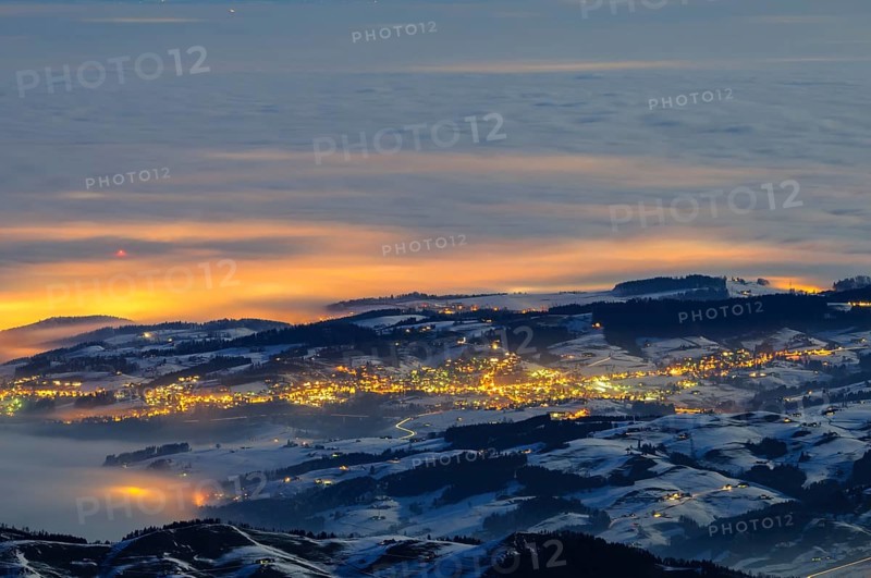 Night shot, long exposure of the 2506 meter high SÃ¤ntis into the wintery, snow-covered, fog-covered foothills of the Alps illuminated by the villages, during a clear full moon night, Canton of Appenzell, Switzerland