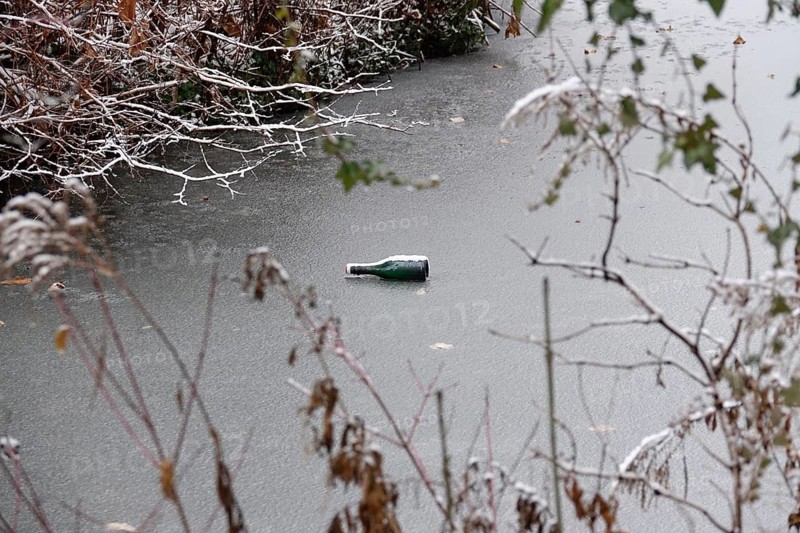 Symbolic picture of garbage in nature, bottle on frozen lake, winter, Germany