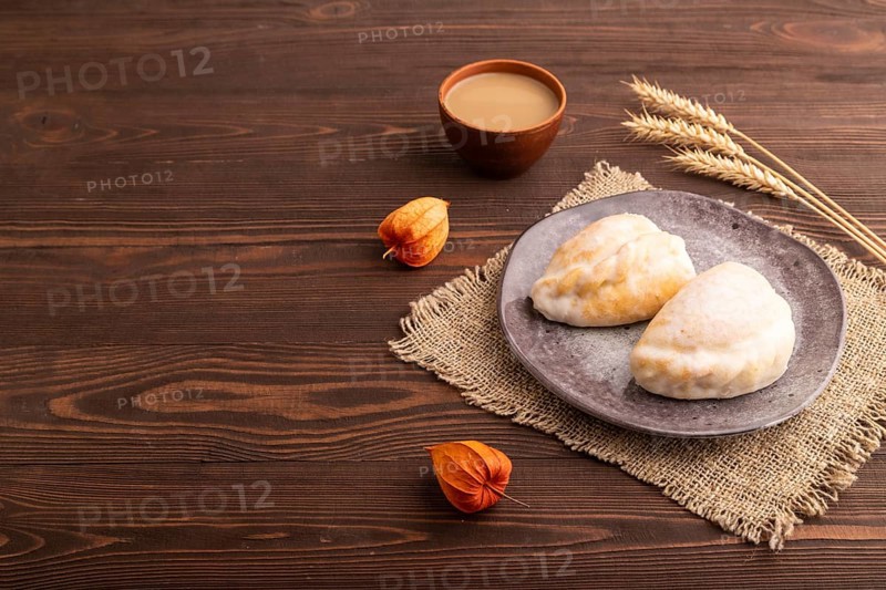 Glazed Pies with Cowberry jam on brown wooden background and linen textile, cup of coffee, side view, copy space