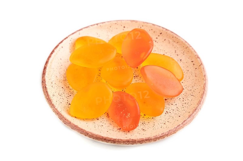 Jelly candies on ceramic plate isolated on white background, side view, close up