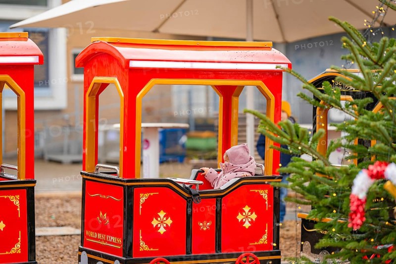 A child sits on a red miniature train next to a Christmas tree at a market, Sindelfingen, Böblingen district, Germany