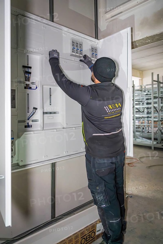 Technician working on a control cabinet, gloves, electrical cables, electrician, new building, Germany