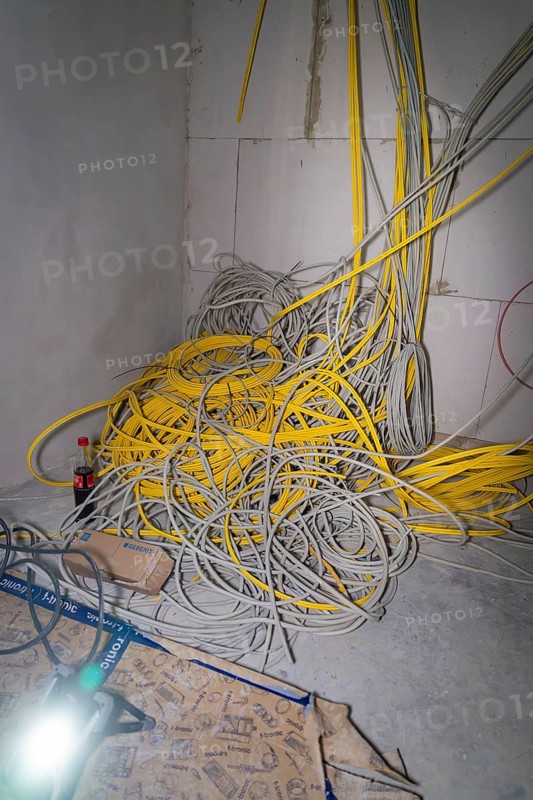 Disordered pile of yellow and gray cables in a corner of a room, electrician, new building, Germany