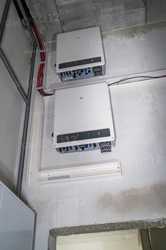Two electronic devices are mounted on a wall, with visible cables and connections, electrician, Neubau, Germany