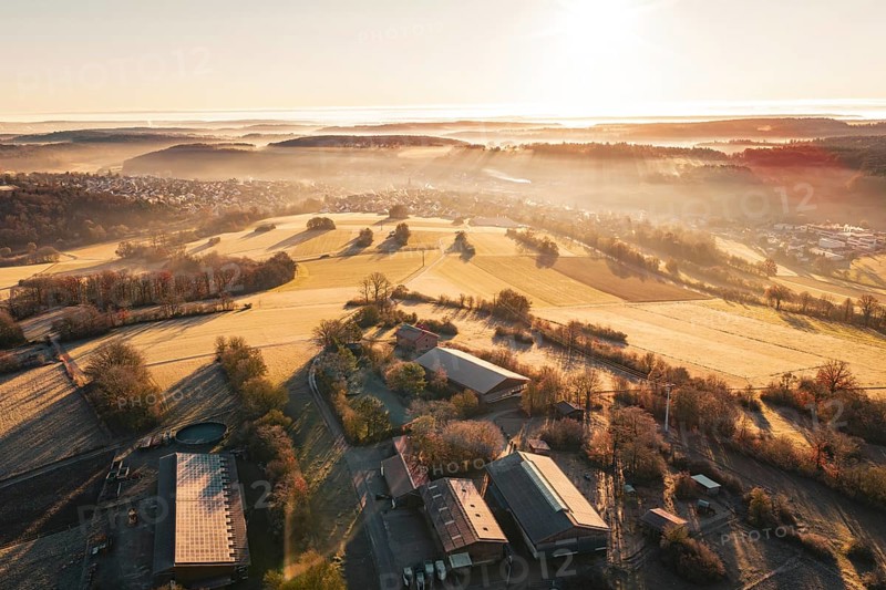 Wide view of fields and farm in fog with gentle sunrise in the distance, Gechingen, Hecken and GÃ¤u region, Calw district, Germany