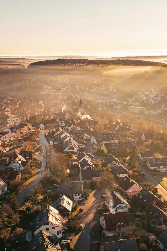 Village bathed in warm sunshine, with light fog and church tower in an autumnal atmosphere, Gechingen, Hecken and GÃ¤u region, Calw district, Germany