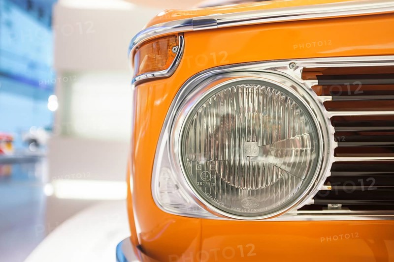 Detailed view, headlights of a BMW 02 series, 1502-2002tii, which was produced from 1966 to 1977. Color: The bright orange paint is often referred to as Inca orange and was a popular color for these models, BMW Welt, Munich, Bavaria, Germany