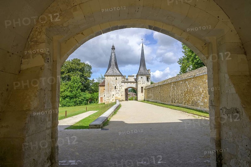 View through archway to the double tower with entrance gate at the Abbey of, Le Bec-Hellouin, Eure, France