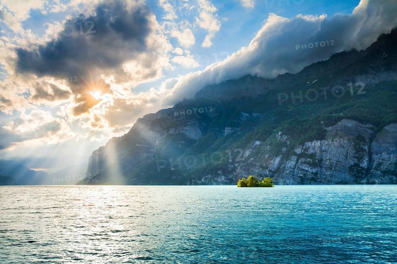 Evening sunshine on Lake Walensee with chive island near Mols, in turquoise water and SchÃ¤ren mountain range and Leistchamm in the background, Canton of St. Gallen, Switzerland