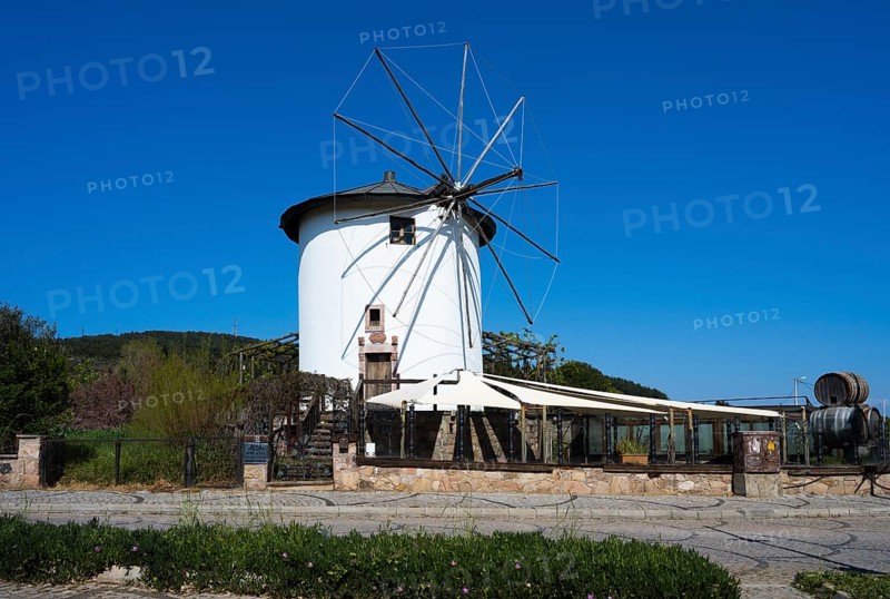 A white windmill with wings in a quiet rural setting under clear skies, Cunda Windmill, Alibey AdasÄ± Island, Cunda AdasÄ±, Ayvalik Islands, Ayvalik, Aegean Sea, Turkey