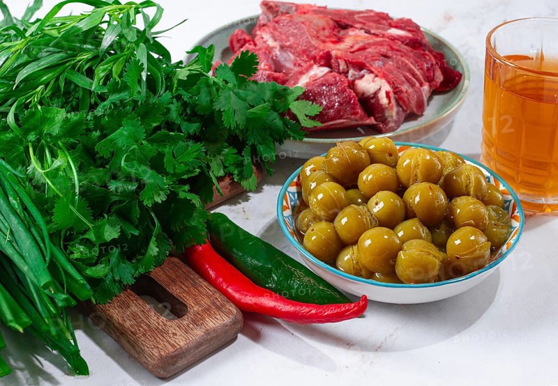 Ingredients for cooking chakapuli, canned tkemali, meat, herbs Georgian cuisine, top view