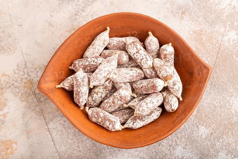 Small smoked Chicken sausages in clay bowl on brown concrete background. top view, close up