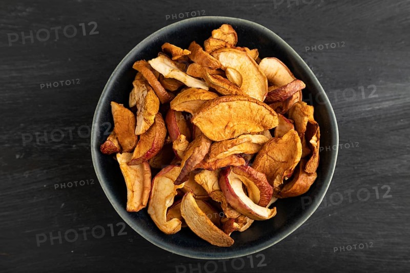 Dried Apples in ceramic bowl on black wooden background. Top view, close up, flat lay. healthy food, minimalism. sweet