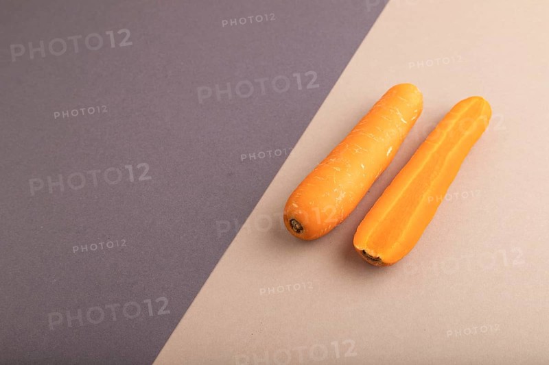 Orange Carrot on beige and gray pastel paper background. Side view, copy space, flat lay. healthy food, vegetable, minimalism