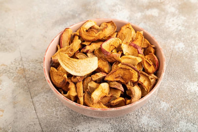 Dried Apples in ceramic bowl on brown concrete background. Side view, copy space, flat lay. healthy food, minimalism. sweet