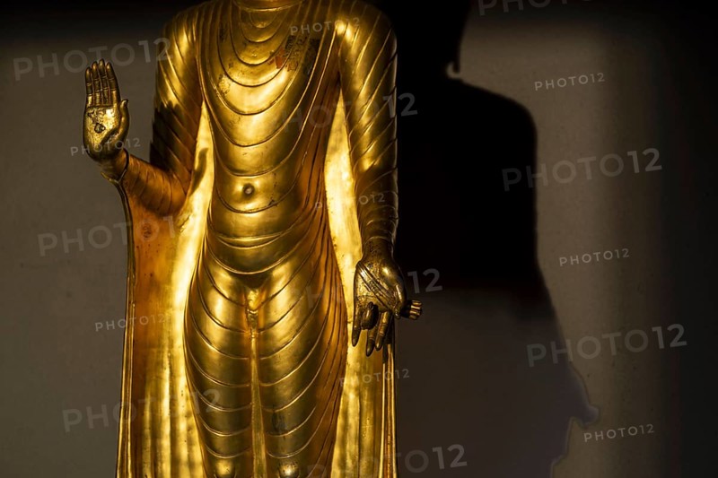 Standing gilded Buddha statue, the right hand (raised, open palm facing outwards) symbolises the Abhaya mudra, the gesture of fearlessness, the left hand (opened downwards in front of the body), this posture is the Varada mudra, the gesture of giving or the gesture of charity, Wat Chana Songkhram, Phra Nakhon, Bangkok, Thailand