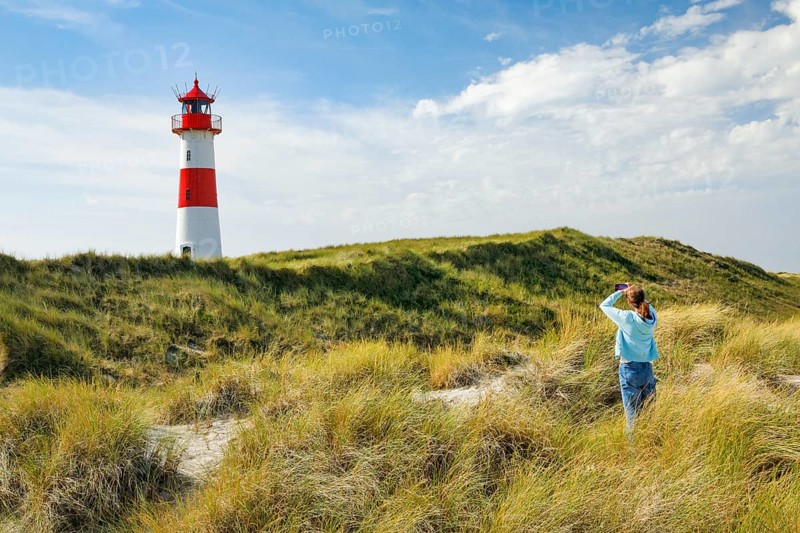 Young Fau takes a photo of the List-Ost lighthouse on his elbow on the island of Sylt, Germany