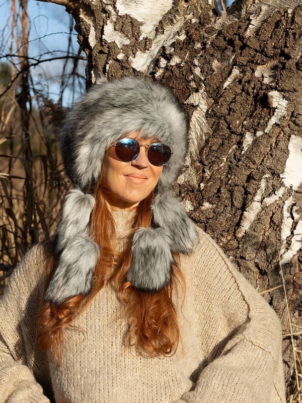 Slender pretty woman with Mongol hat, red hair and warm winter colors between birch forest and reeds