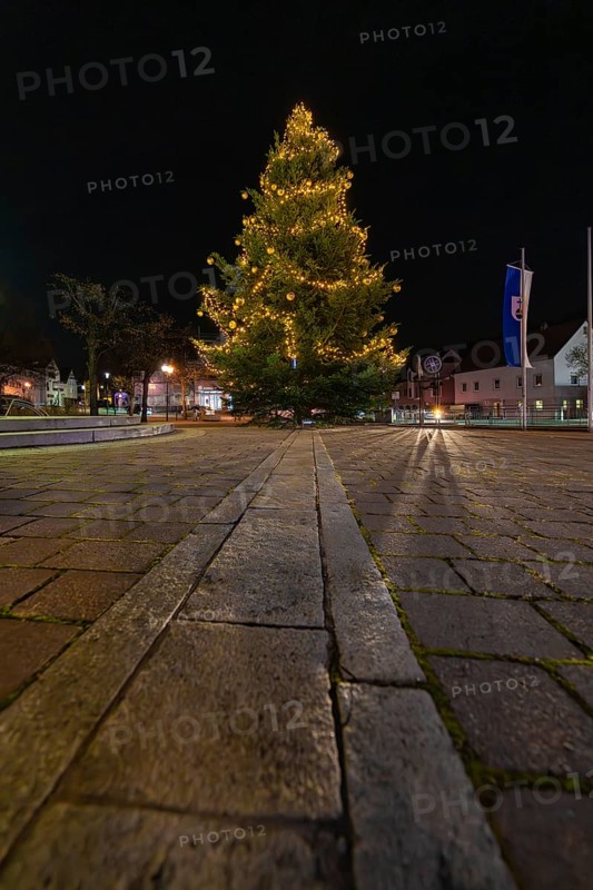 A festively lit Christmas tree at night on a paved square, Aidlingen, Böblingen district, Germany