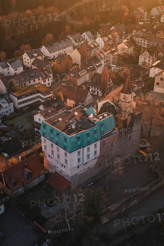 Aerial view of a village with a castle in warm evening light surrounded by trees, Dillweisenstein, Pforzheim, Germany