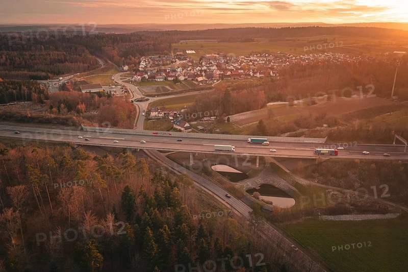 Sunset over a rural village with a motorway leading through fields and forests, A8 motorway, Germany