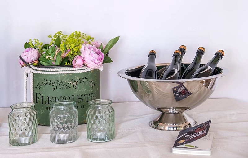 Flower arrangement and bottles in a wine cooler on a table, Rhineland-Palatinate, Germany