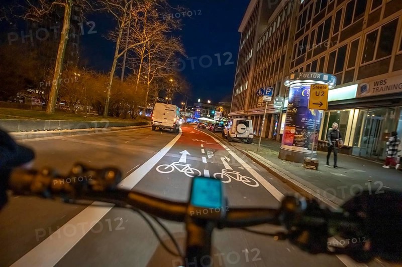 Cycling in the city, in the dark, in the evening, cycling on a bike lane, marked, Huyssenallee, downtown Essen, North Rhine-Westphalia, Germany