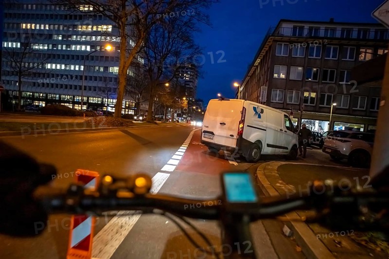 Cycling in the city, in the dark, in the evening, cycling on a bike lane, marked, delivery vehicle blocking the cycle path, Huyssenallee, in downtown Essen, North Rhine-Westphalia, Germany