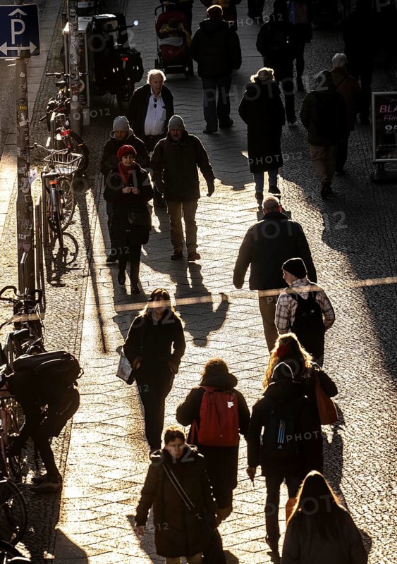 Passers-by on a FriedrichstraÃŸe sidewalk in Berlin, shade, low sun, winter, Germany