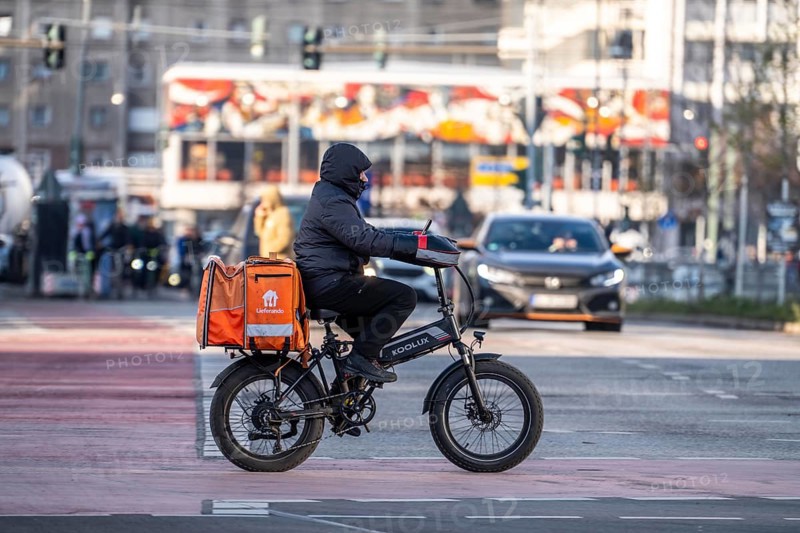 Lieferando delivery service driver, with moped-style e-bike, fat bike, model Koolux, at delivery, AlexanderstraÃŸe, Berlin