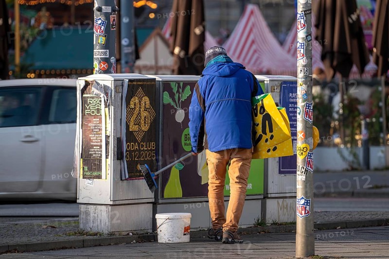 Man sticks posters to electrical boxes near Alexanderplatz, Berlin, Germany