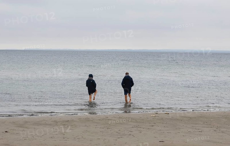 A couple standing barefoot in the cold seawater of the Baltic Sea, Scharbeutz, 28.11.2025, Scharbeutz, Schleswig-Holstein, Germany