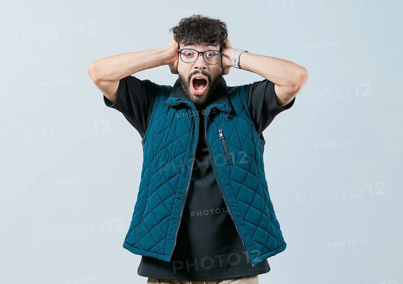 Panicked young man holding her head isolated. Worried and alarmed man holding her head