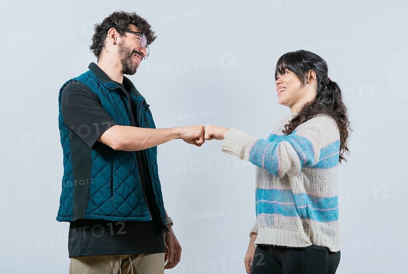 Smiling couple bumping fists, isolated. Attractive couple smiling and bumping fists