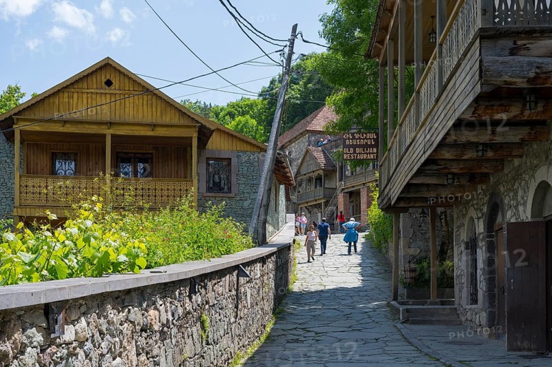 Village street lined with old buildings with wooden verandas flanked by green vegetation under a clear sky, Old Town, Sharambeyan Street, Dilijan, Delijan, Delijan, Tavush Province, Armenia