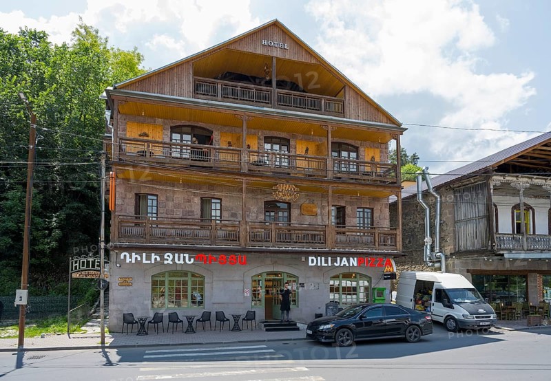 Three-story hotel with wooden faÃ§ade and pizzeria, surrounded by trees and cars on the street, Dilijan, Delijan, Delijan, Tavush Province, Armenia